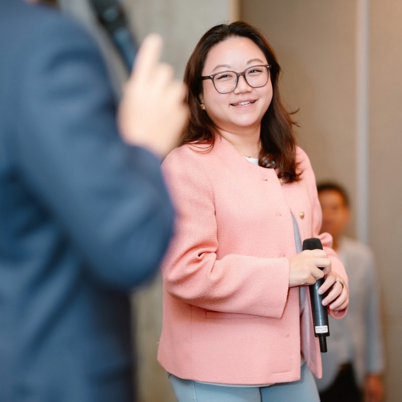 Gabrielle Loo in a pink blazer, holding a microphone