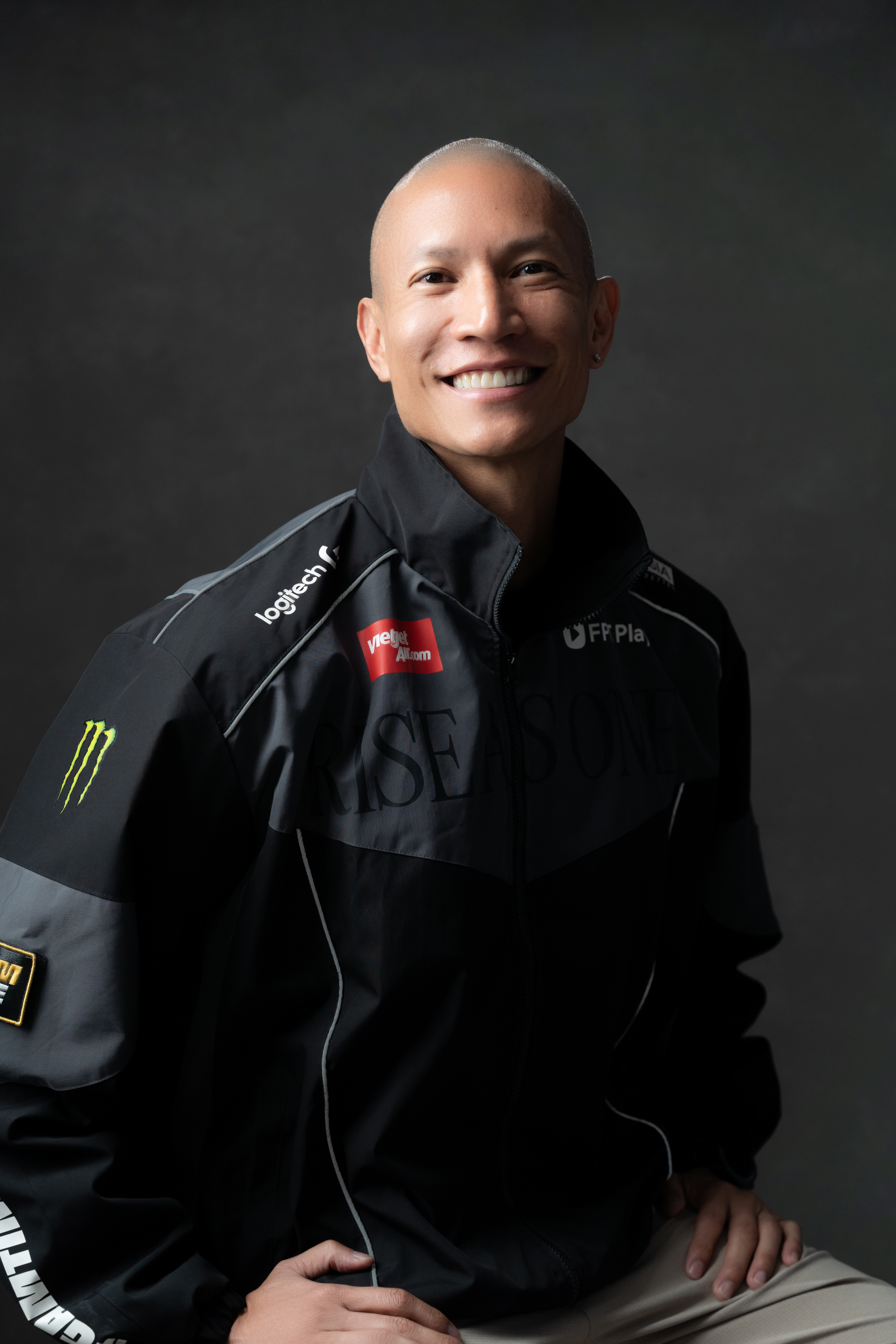 TK Nguyen in a black zip-up jacket with racing sponsor logos, smiling